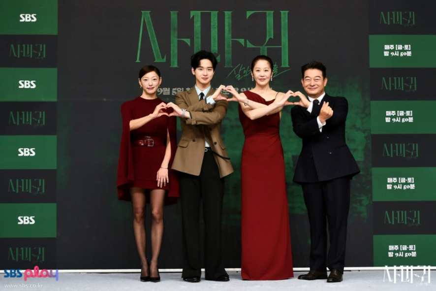 출연진 4명이 어두운 배경 앞에서 밝은 미소를 지으며 손으로 하트 포즈를 만들고 있습니다. 배우들은 버건디/레드 계열의 의상을 중심으로 스타일링했으며, 드라마의 제목('사마귀')과 방영 정보가 배경에 보입니다. 출연진 4명이 어두운 배경 앞에서 밝은 미소를 지으며 손으로 하트 포즈를 만들고 있습니다. 배우들은 버건디/레드 계열의 의상을 중심으로 스타일링했으며, 드라마의 제목('사마귀')과 방영 정보가 배경에 보입니다.
