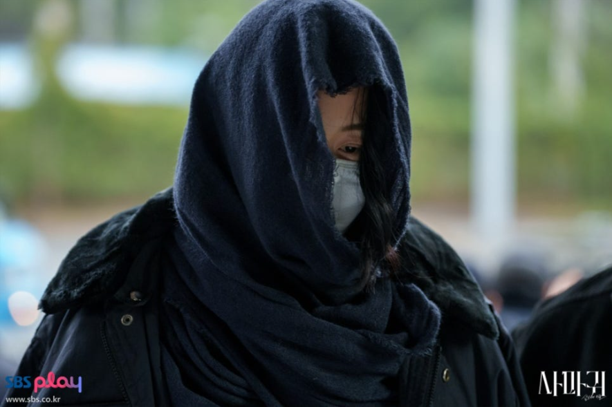 배우 고현정으로 보이는 인물이 어두운 색 스카프나 천으로 머리와 얼굴을 깊게 가리고 마스크를 착용한 모습입니다. 얼굴을 거의 드러내지 않고 고개를 숙인 채 음침하고 비밀스러운 분위기를 풍겨 극 중 캐릭터의 어두운 상황을 짐작하게 합니다. 배우 고현정으로 보이는 인물이 어두운 색 스카프나 천으로 머리와 얼굴을 깊게 가리고 마스크를 착용한 모습입니다. 얼굴을 거의 드러내지 않고 고개를 숙인 채 음침하고 비밀스러운 분위기를 풍겨 극 중 캐릭터의 어두운 상황을 짐작하게 합니다.